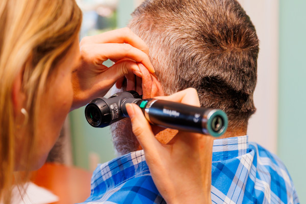 A patient receiving a hearing exam from Dr. Sally Ware