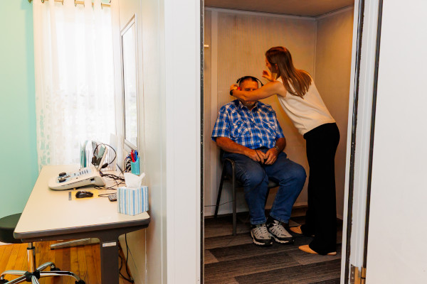 A patient getting set up for a hearing test in the hearing booth